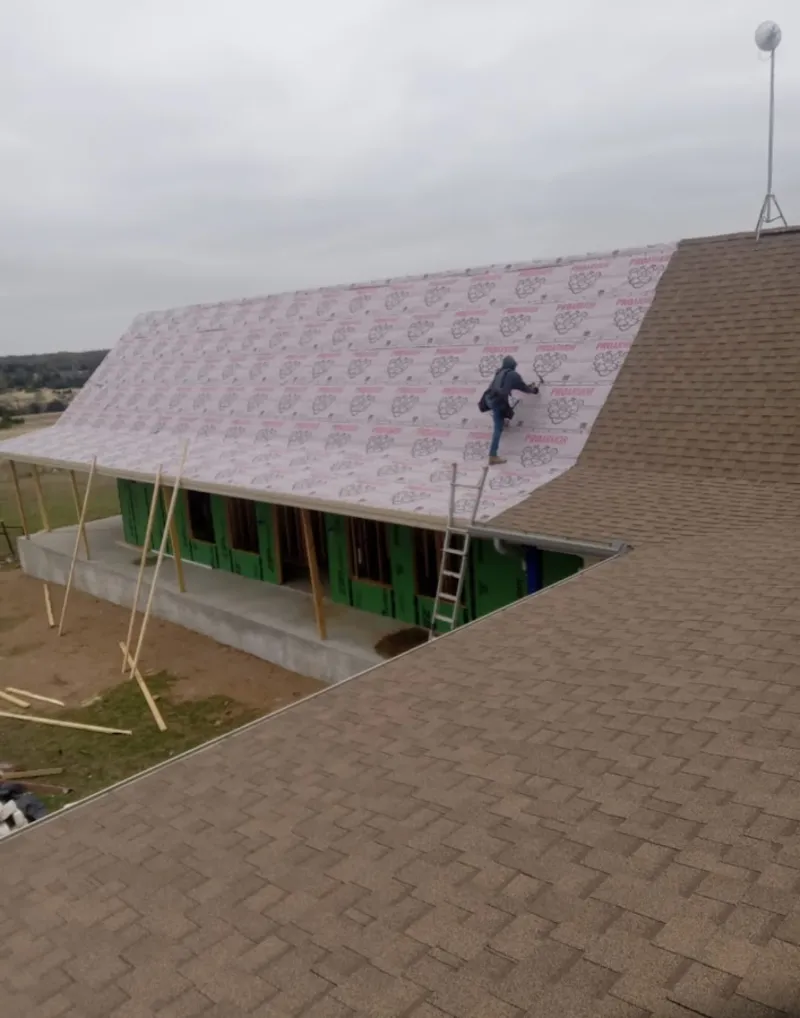 Worker preparing underlayment for a metal roof installation in Collingswood